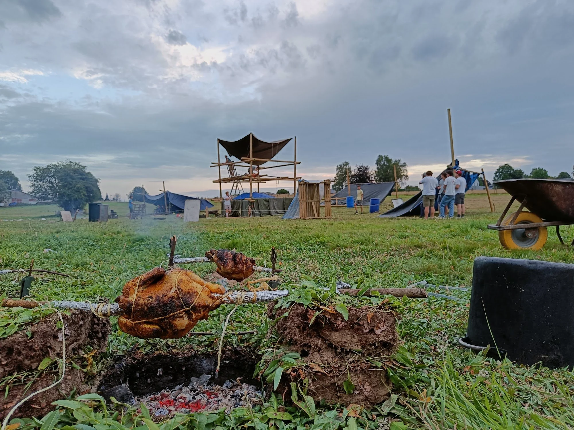 Een zelfgesjorde toren op het kampterrein, met kip die boven het vuur gaart