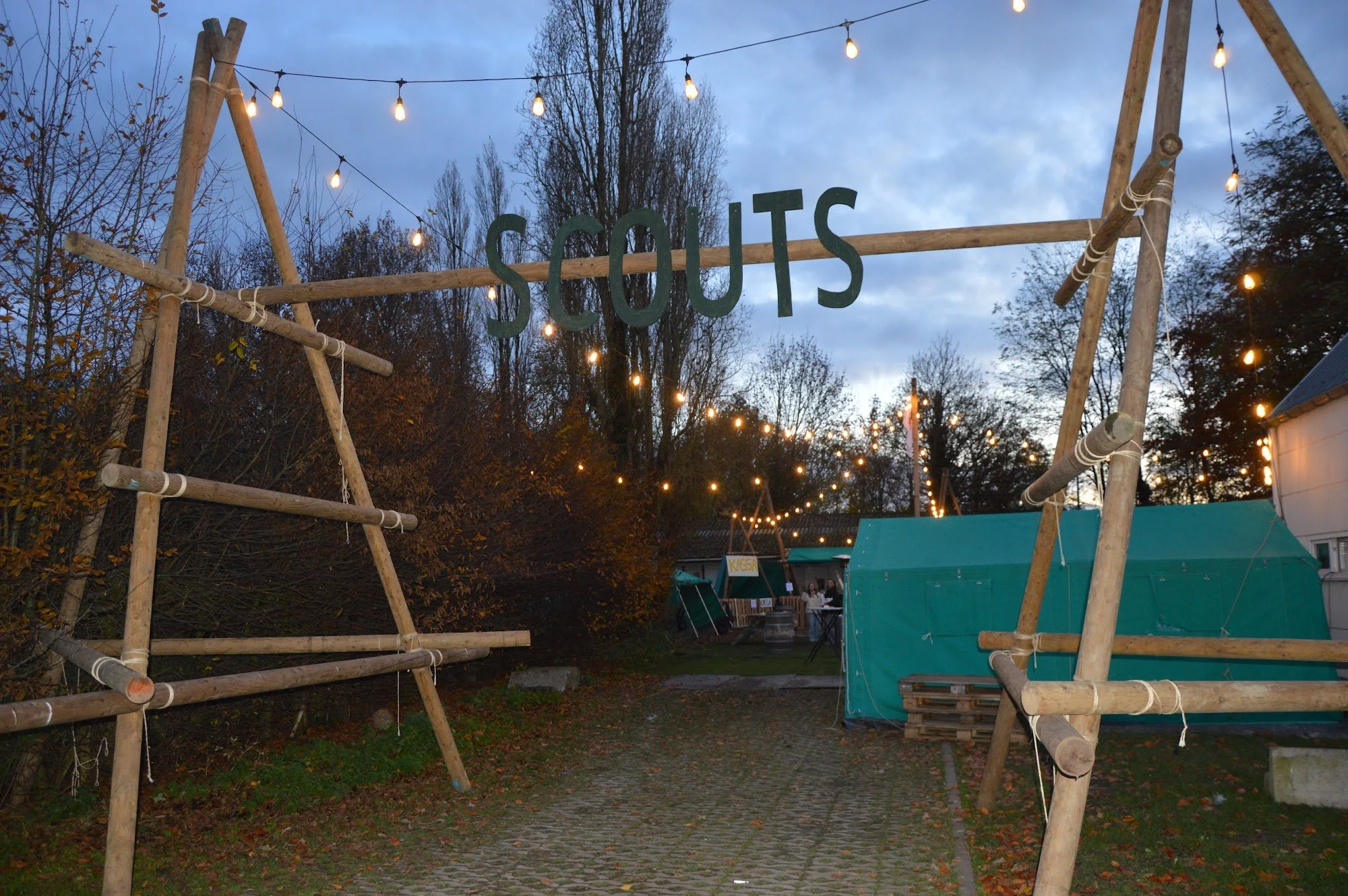 Een gesjorde toegangspoort met het woord SCOUTS en lichtjes, aan ons lokaal